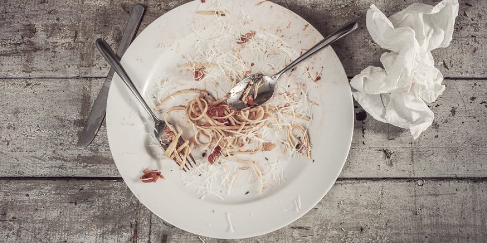 Plate of spaghetti at the end of a meal on a wooden table